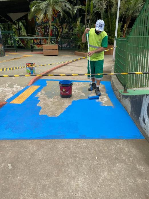 homem pinta piso que está delimitado por faixa zebrada. #paratodosverem