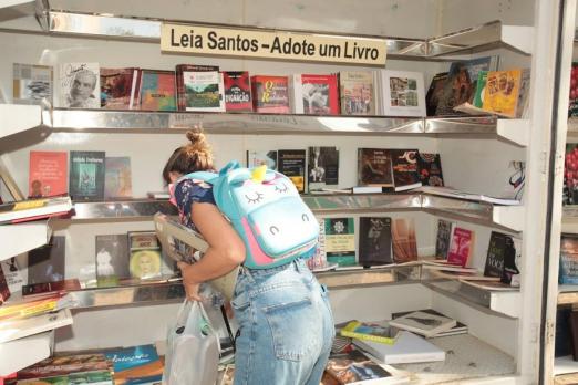 mulher pega livro em estande do projeto #paratodosverem