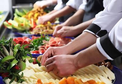 Bancada com vários alimentos. Mãos, em close,manipulam frutas. #Pracegover