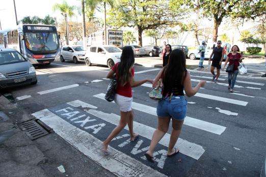 Pedestres atravessam em faixa com a inscrição faixa viva #pracegover 