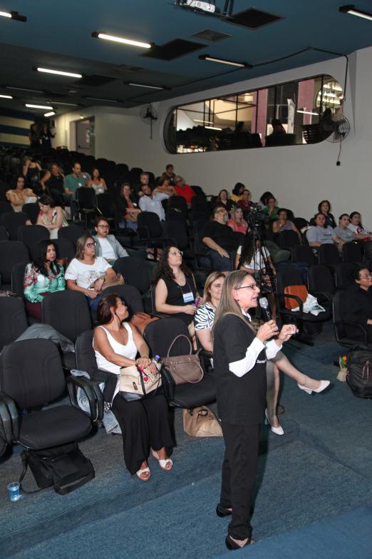 palestrante fala com mulheres sentadas assistindo #pracegover 