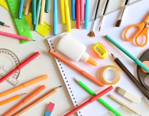 materiais escolas, como lápis, cola, apontador, tesoura, pinceis e outros dispostos sobre uma mesa. #paratodosverem
