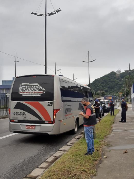 Micro-ônibus está parado em via. Ao lado há guardas municipais. #Paratodosverem