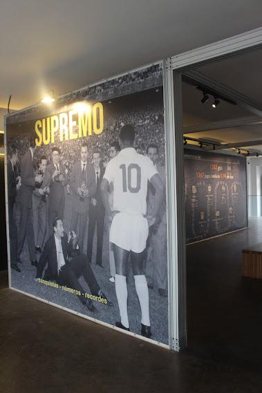 painel com uma foto mostrando o Rei Pelé de costas, com a camisa 10 e algumas pessoas engravatadas diante dele. No alto se lê Supremo. #paratodosverem