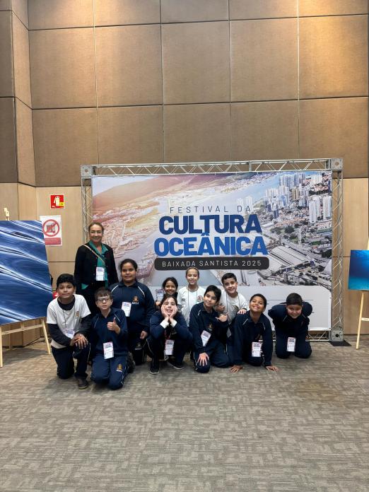 alunos posam na frente de placa do festival #paratodosverem