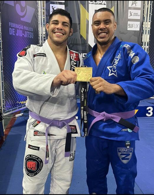 Pedro e Luiz abraçados lado a lado e segurando medalha de ouro. #paratodosverem