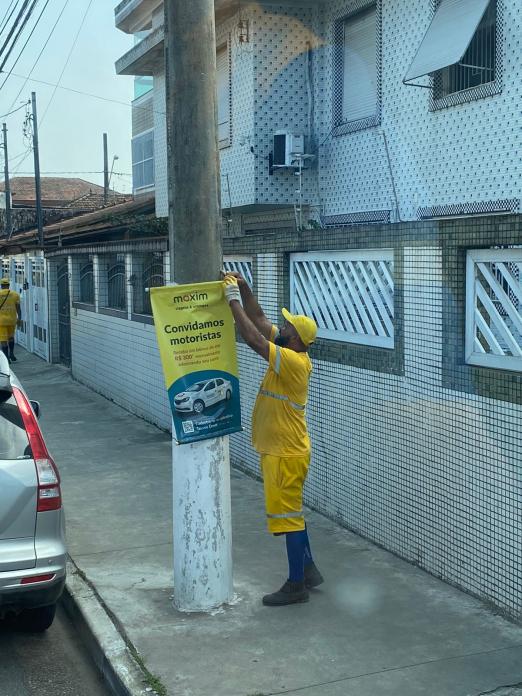 operário usando uniforme retira banner preso em poste. #paratodosverem