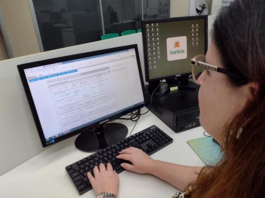 mulher estão sentada diante de desktop. Ela digita no teclado. #paratodosverem