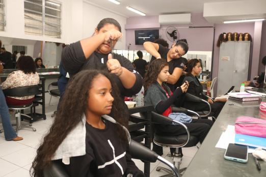 alunos fazem cabelo de clientes em salão.#paratodosverem