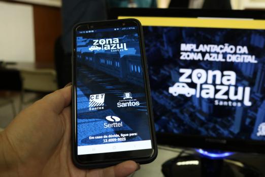 computador e celular estão com aplicativo do zona azul na teça #pracegover 