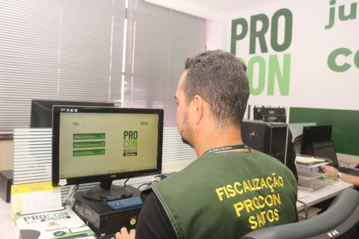agente do procon uniformizado diante de computador. #paratodosverem