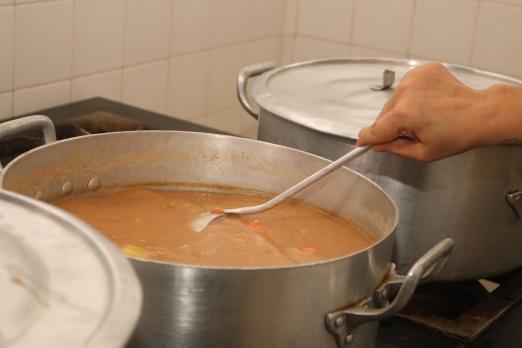 mão mexe em comida dentro de panela. #paratodosverem 