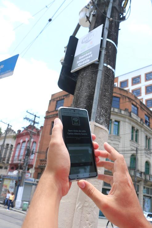 pessoa acessa internet com celular ao lado de placa #paratodosverem 