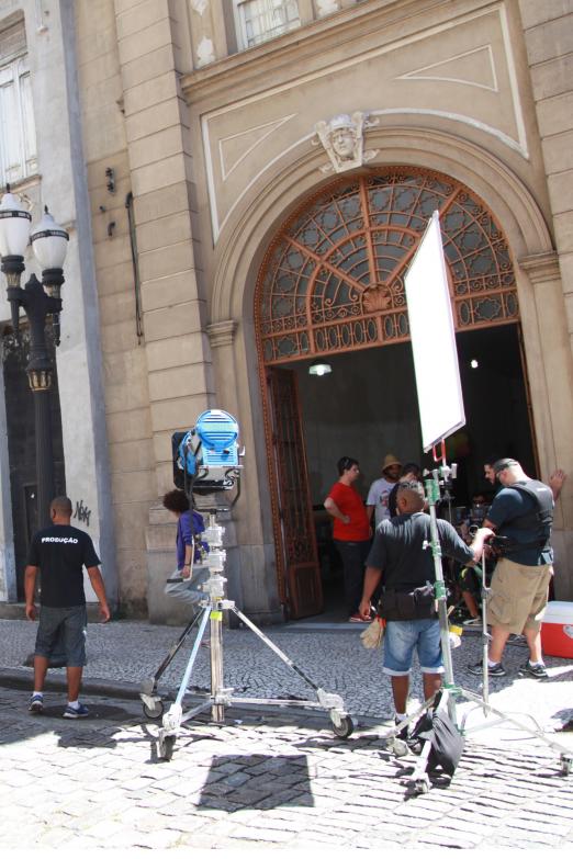 Filmagem realizada ao ar livre. Câmeras estão nas ruas junto a outros equipamentos de vídeo. Operadores mexem em equipamentos #Paratodosverem