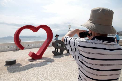 Homem fotografa letreiro com a palavra santos e coração #pracegover 