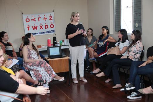 servidorias assistem a curso com professora falando no meio da sala #pracegover 