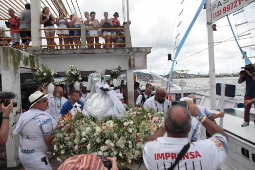 Imagem de Iemanjá está entrando em barco para iniciar procissão marítima. #Pracegover