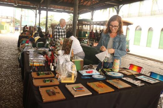 pessoas olhando produtos em feira criativa #paratodosverem