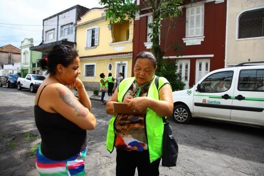 agente aborda mulher na rua com prancheta #pracegover 