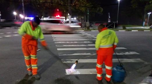 dois operários pintam faixa de pedestres #pracegover 