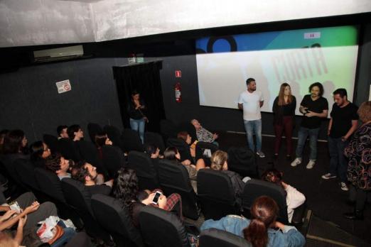 Pessoas estão em cinema, algumas delas em pé #pracegover 