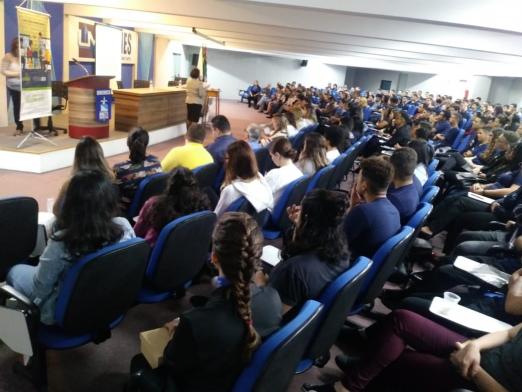 pessoas sentadas no auditório durante o evento #pracegover 