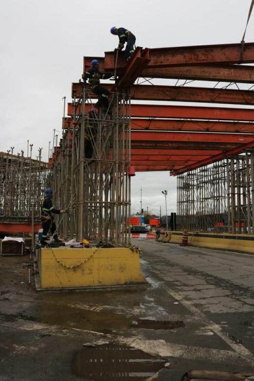 Três homens uniformmizados trabalham sobre cimbramento de viaduto