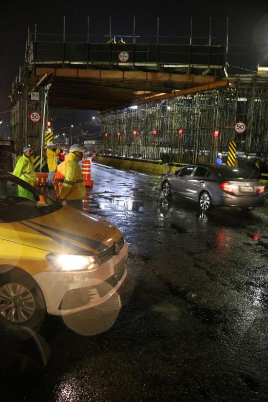 À noite, com a pista molhada de chuva, carro passa sob estrutura metálica da Avenida Martins Fontes observados por dois agentes uniformizados da CET