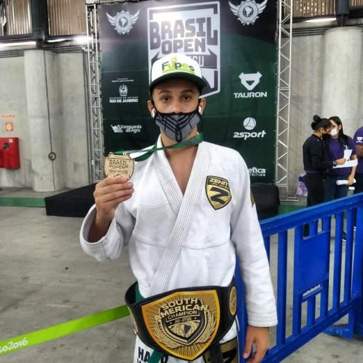 Atleta exibe medalha e cinturão conquistados na competição. #paratodosverem