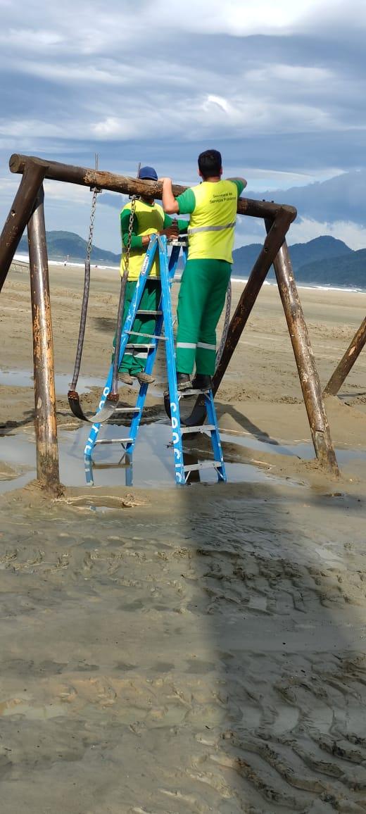 homens instalam equipamento na praia #paratodosverem