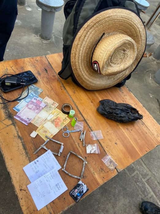 dinheiro e cigarros de maconha sobre uma mesa. #paratodosverem