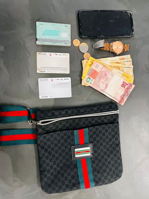 carteira, dinheiro, cartões, relógio e celular dispostos sobre uma mesa. #paratodosverem 