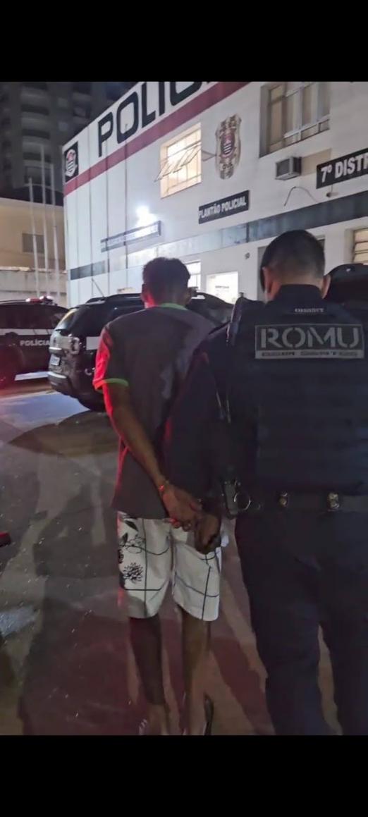 homem é conduzido por guarda municipal. Ambos estão de costas. #paratodosverem