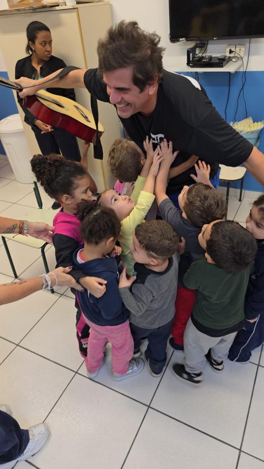 crianças abraçam músico. #paratodosverem