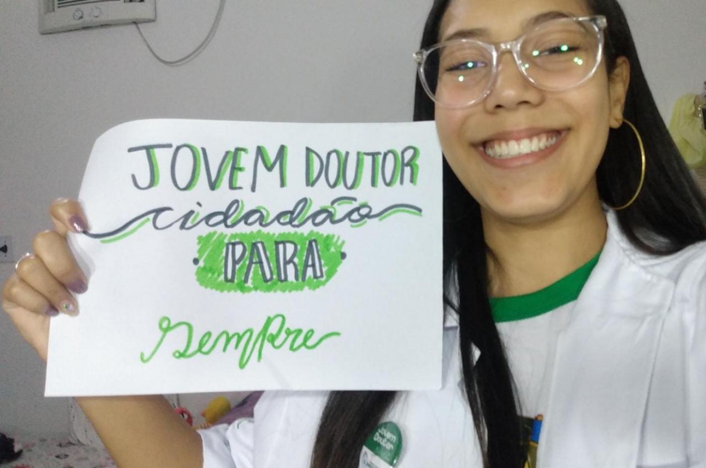 jovem mostra cartaz que diz jovem doutor cidadão para sempre #paratodosverem