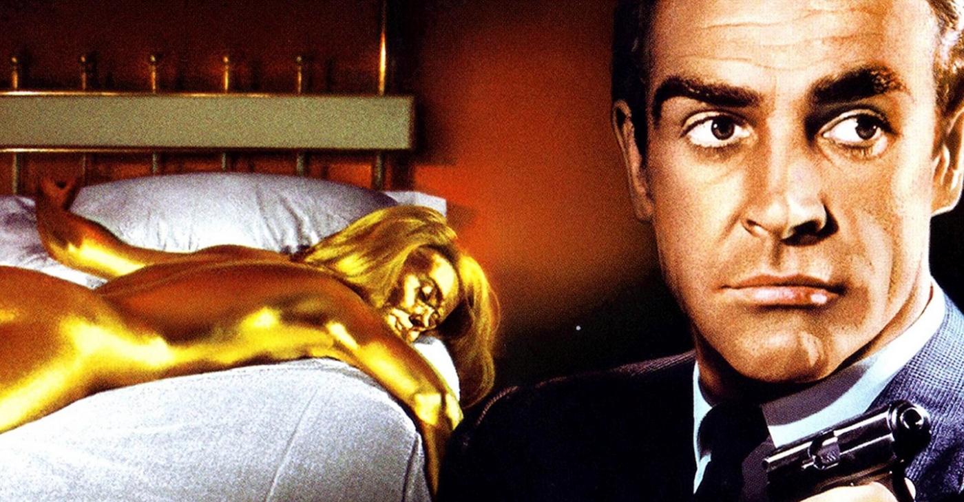 Cena de 007 contra goldfinger tem o agente 007 com mulher dourada deitada em cama #pracegover  