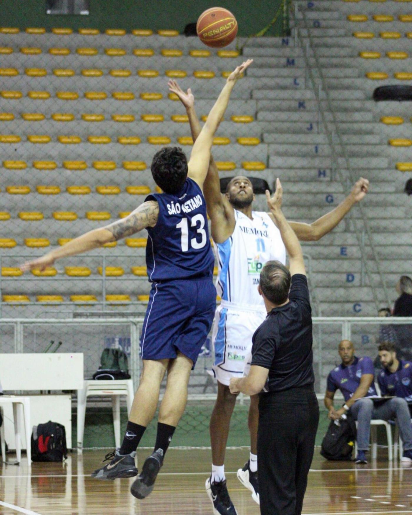 dois jogadores estão disputando bola no ar com os braços esticados. #paratodosverem