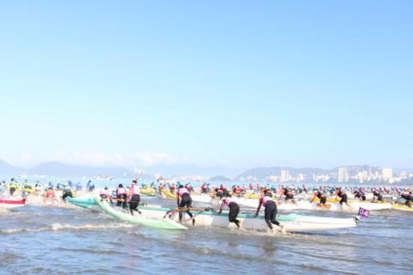 pessoas entrando com canoas havaianas no mar #paratodosverem
