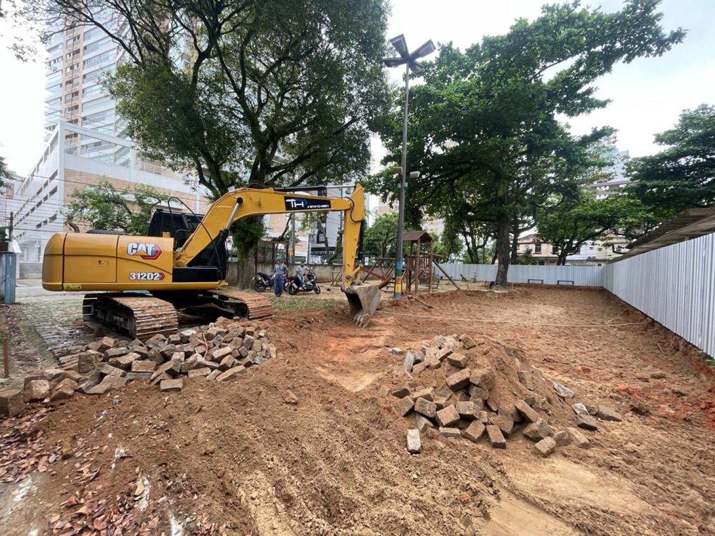 trator está cavando solo de terra em área tapumada. #paratodosverem 