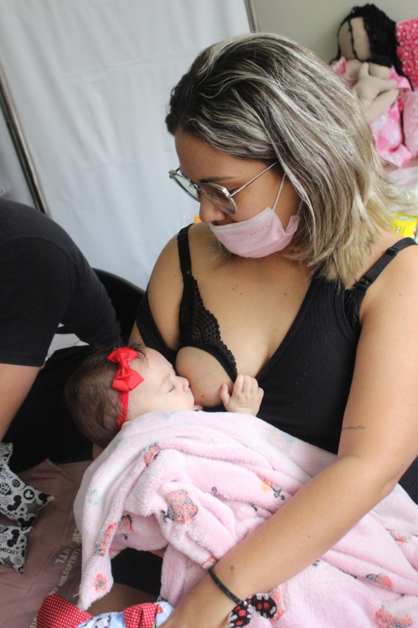 bebê é amamentado no peito. Mão olha para a criança. #paratodosverem