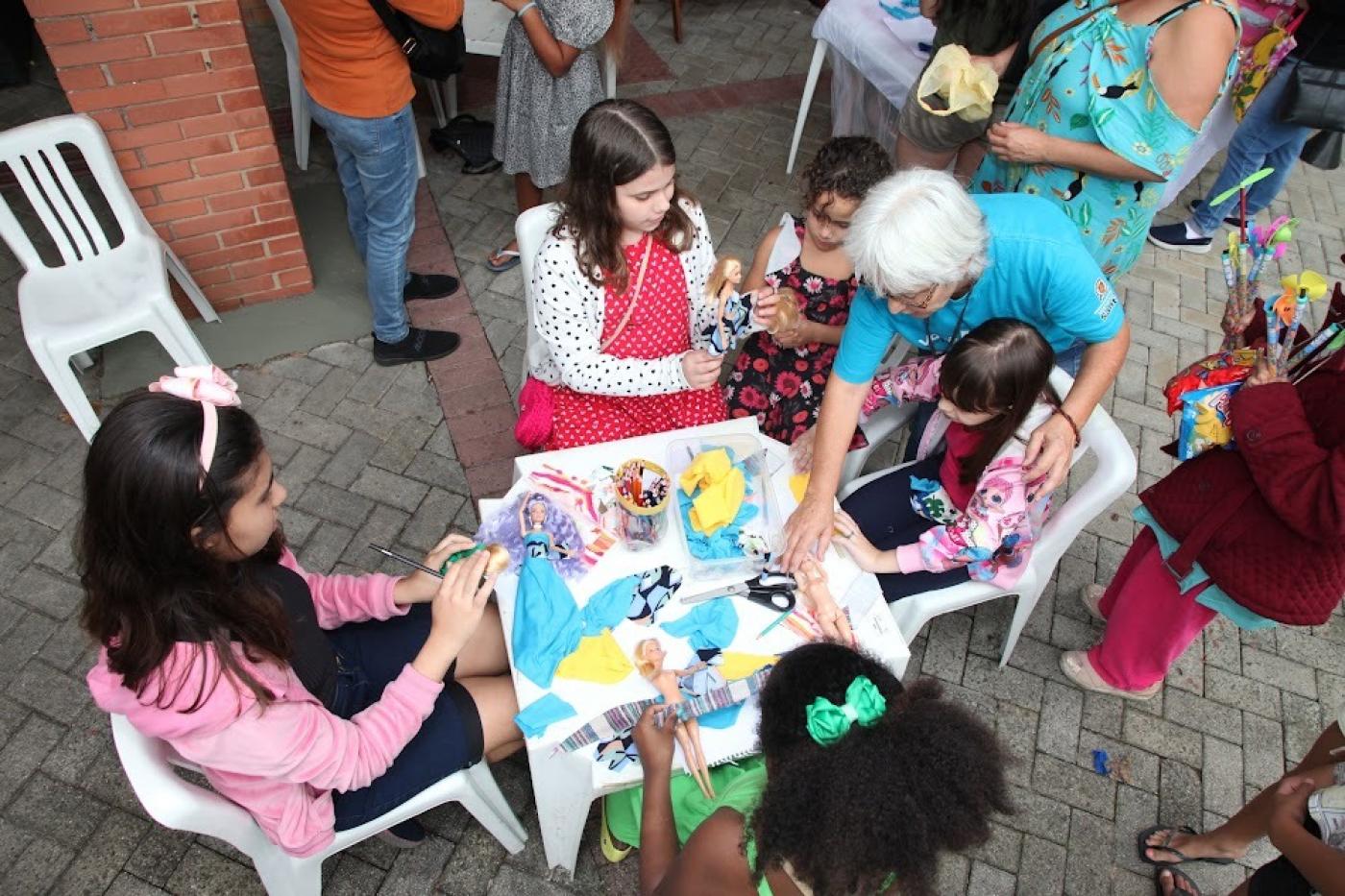 crianças pintando em mesa no parque #paratodosverem