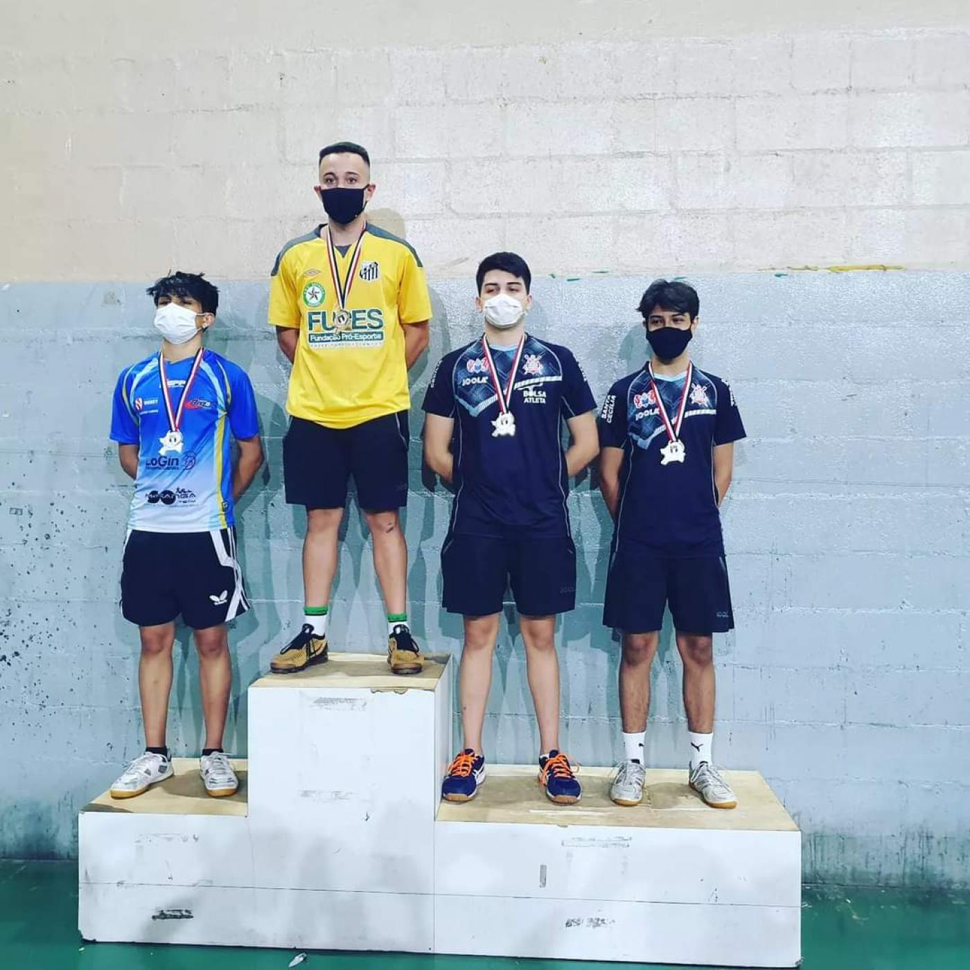 Quatro atletas no pódio com medalhas #paratodosverem