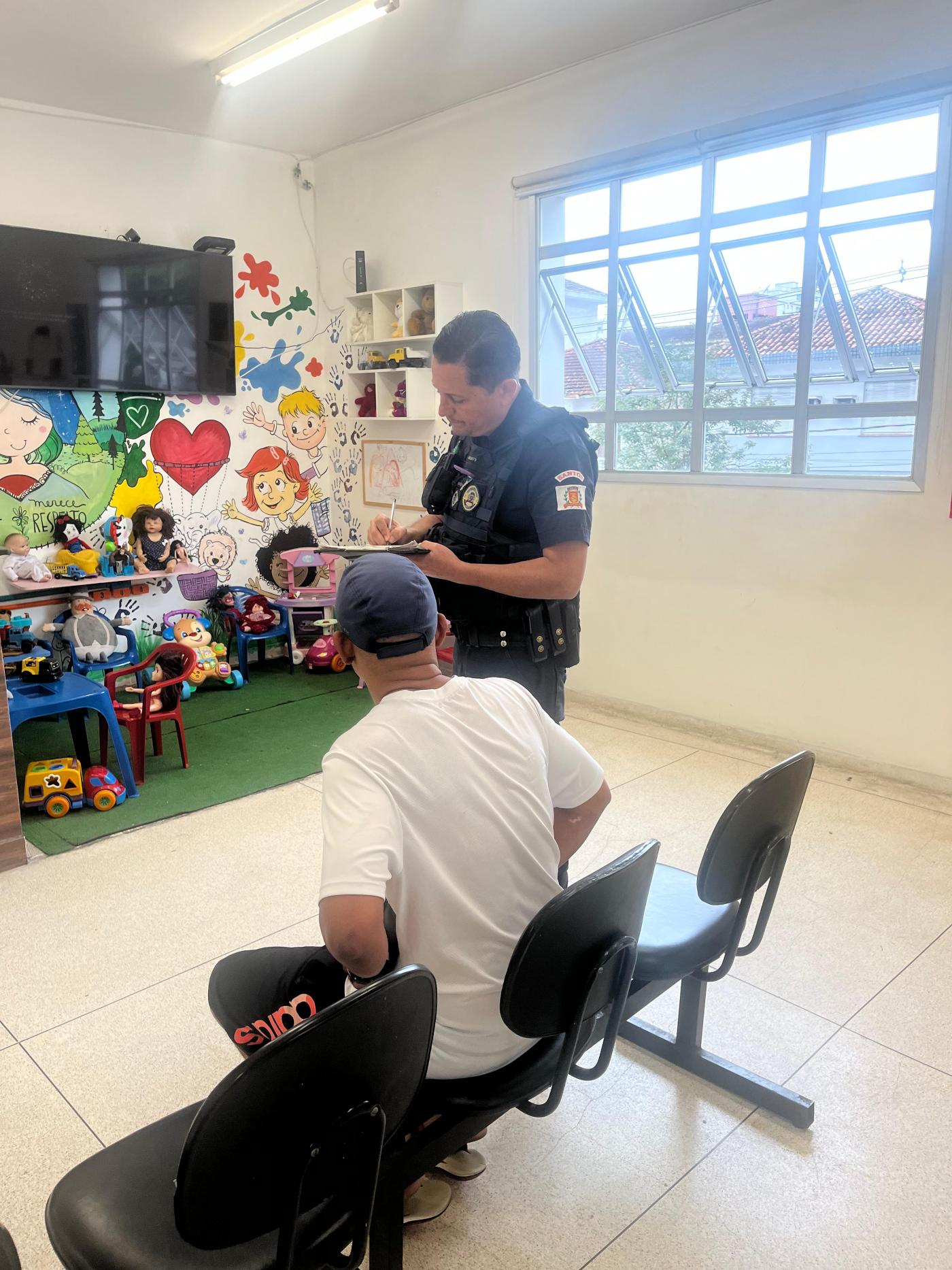 homem está sentado em sala do lado de guarda em pé. #paratodosverem