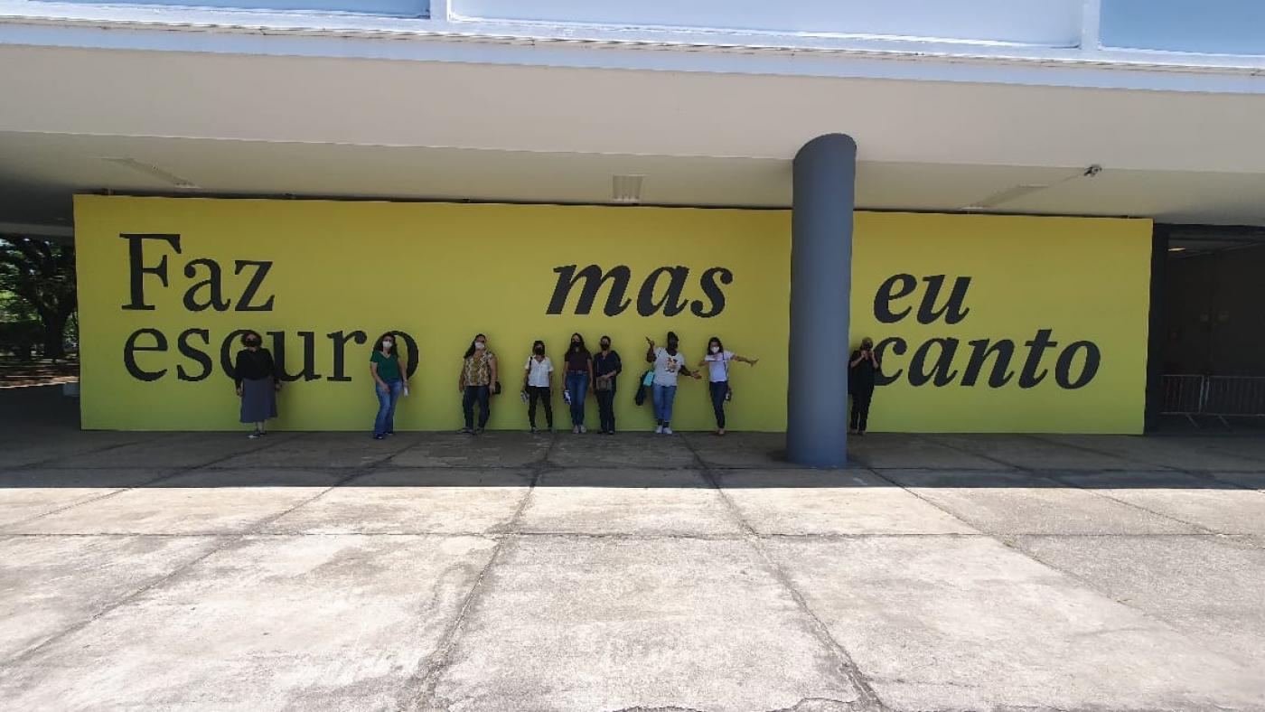 professoras em frente de painel escrito faz escuro mas eu canto #paratodosverem 