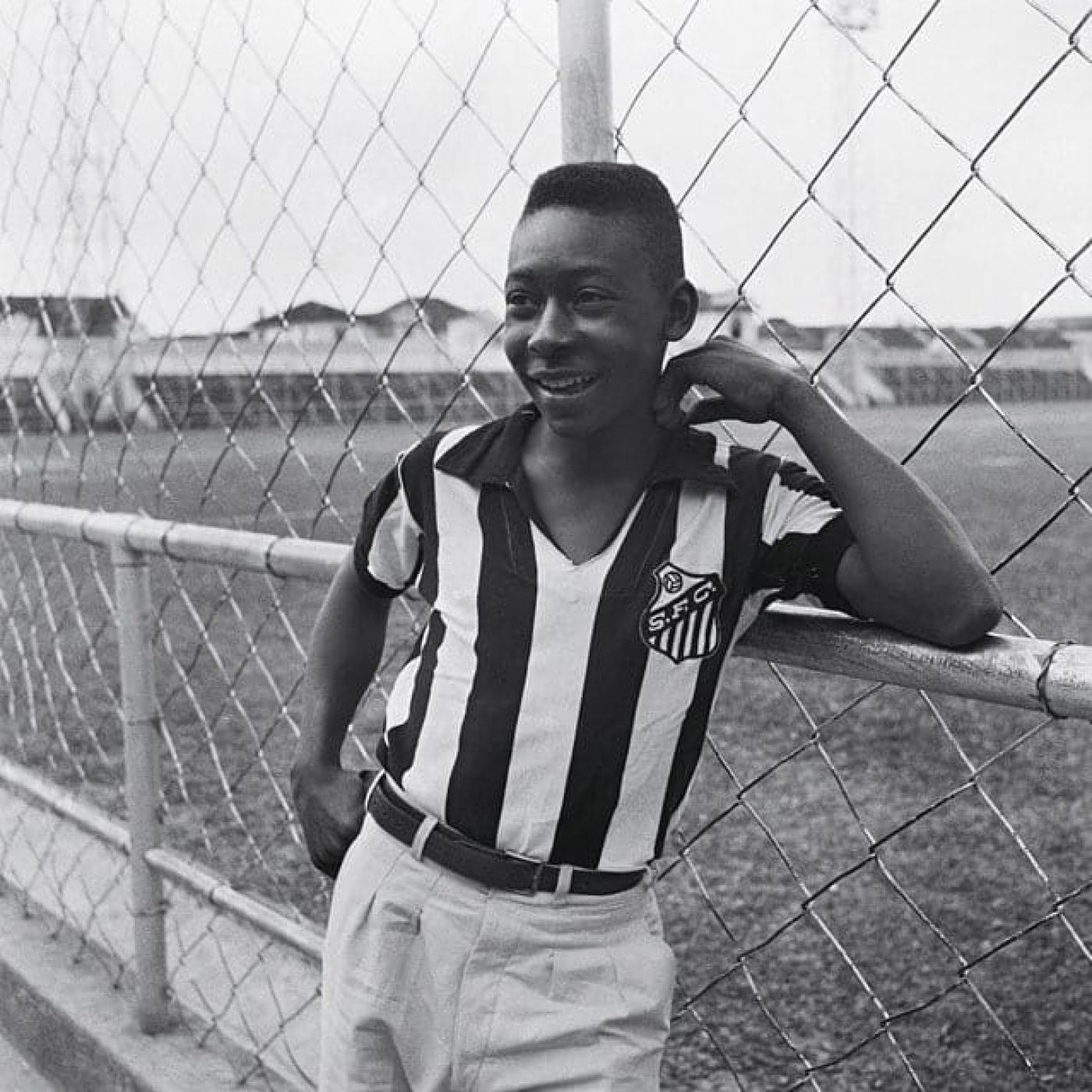 Pelé ainda jovem com camisa do Santos encostado no alambrado #paratodosverem