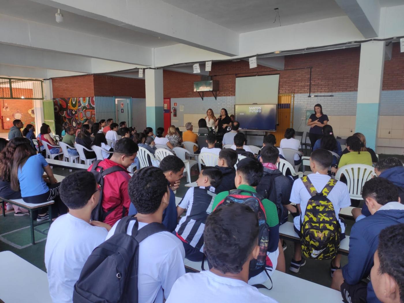 alunos sentados ouvindo apresentação #paratodosverem 