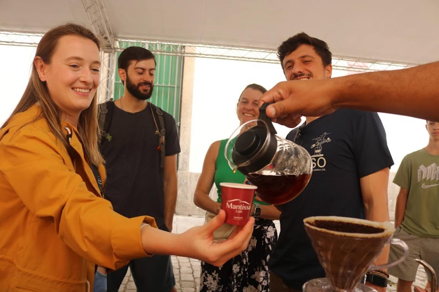 mão serve café para mulher em estande. #paratodosverem