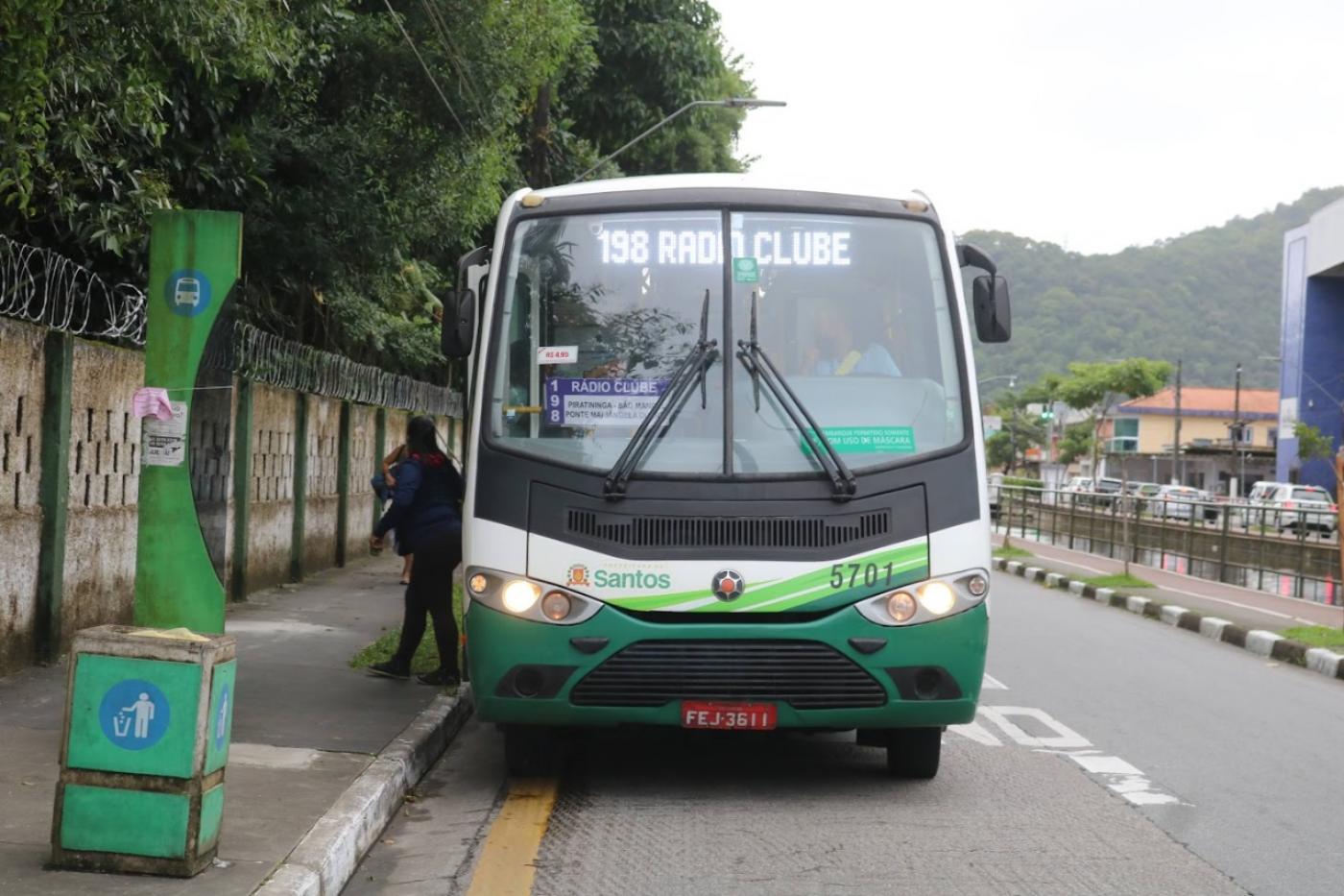 ônibus está parado em ponto em avenida, entre muro de edificação e um canal. #paratodosverem