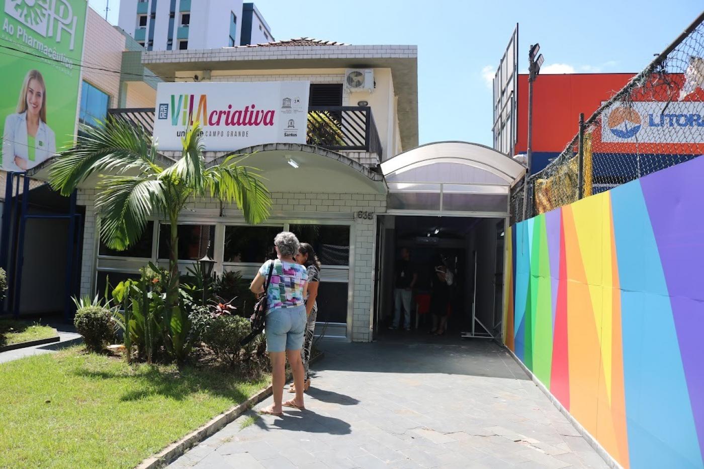 fachada de vila criativa com mulher de costas para a foto entrando na unidade. #paratodosverem 