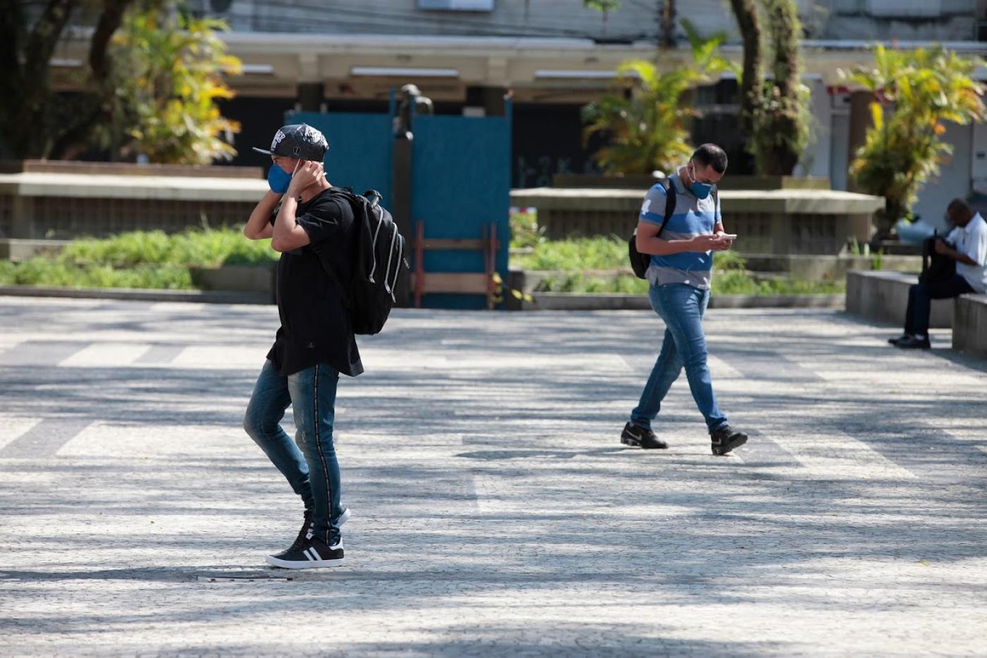 Homem está caminhando em praça e usando máscara. #Paratodosverem